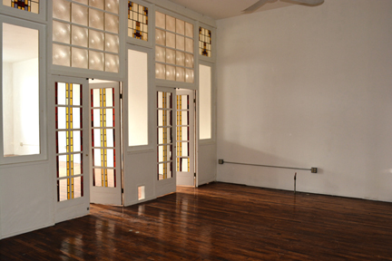 Light shimers through the two sets of stained glass double doors that devide the front and center spaces of loft 2F in this photograph.